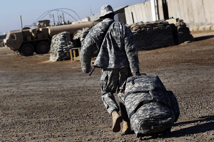 U.S. Army Sgt. Omar Sprott, from Brooklyn, New York, of the 115th Brigade Support Battalion carries his luggage in preparation for leaving Camp Kalsu near Hillla, Iraq December 6, 2011. (© Shannon Stapleton / Reuters)