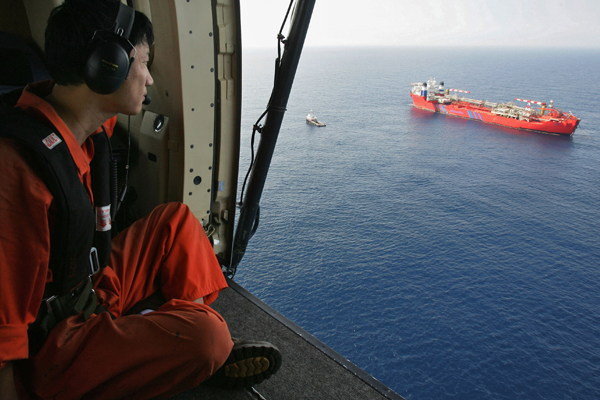 A helicopter flies past an oil production vessel in the South China Sea, May 23, 2006