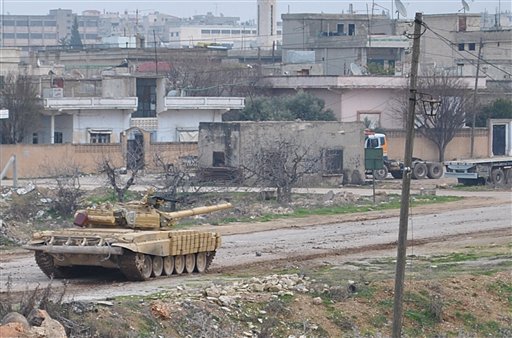 A Syrian forces tank moves along a road during clashes with the Syrian army defectors, in the Rastan area in Homs province, central Syria, on Monday Jan. 30, 2012. (AP)
