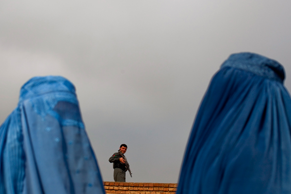 Women line up as a policeman keeps watch during the distribution of winter assistance in Kabul. (Reuters/Ahmad Masood)