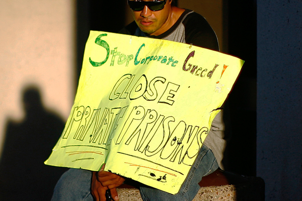 A protester displays a placard reading "Stop corporate greed. Close private prisons" as he takes part in an Occupy Phoenix demonstration on Oct. 17, 2011 (Reuters/Eric Thayer)