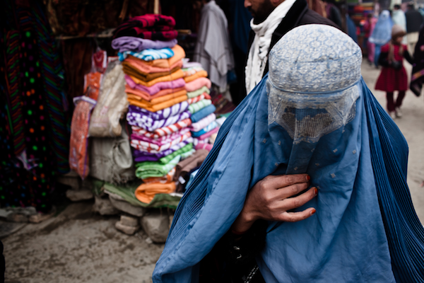 A woman in a burka walks through a market in a heavily populated Pashtun neighborhood on the outskirts of Kabul, Afghanistan, Dec. 19, 2011 (Erin Trieb/VII/GlobalPost)