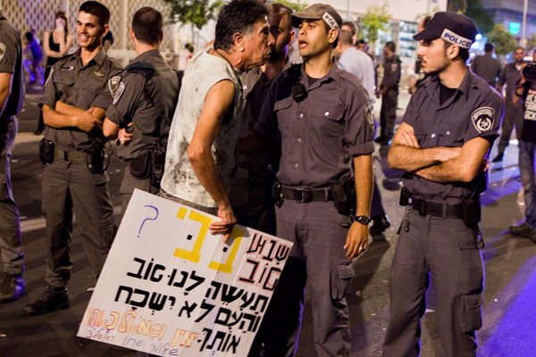 In this Aug. 7, 2011, photo, Israeli police officers line up in front of a protester at the end of a rally in central Tel Aviv, Israel.