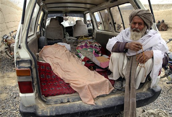 An elderly Afghan man sits next to the covered body of a person who was allegedly killed by a U.S. service member, in a minibus in Panjwai, Kandahar province south of Kabul, Afghanistan, Sunday, March 11, 2012 (AP Photo/Allauddin Khan)