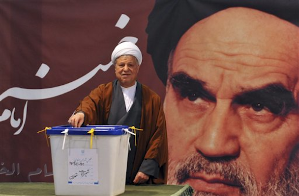 In front of a portrait of late Iranian leader Ayatollah Khomeini, former President Akbar Hashemi Rafsanjani casts his ballot for the parliamentary elections at a polling station in Tehran, Iran, Friday, March 2, 2012 (AP Photo/ISNA, Ruhollah Vahdati)