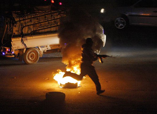 A Syrian rebel runs with his AK-47 towards a Syrian army checkpoint in a suburb of Damascus, Syria, on Saturday March 17, 2012 (AP)