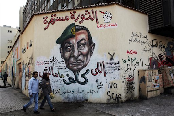 In this Thursday, March 22, 2012 photo, an Egyptian couple walks past a mural depicting military ruler Field Marshal Hussein Tantawi, on the left side of the face and ousted president Hosni Mubarak, right side, in Cairo, Egypt (AP Photo/Nasser Nasser)