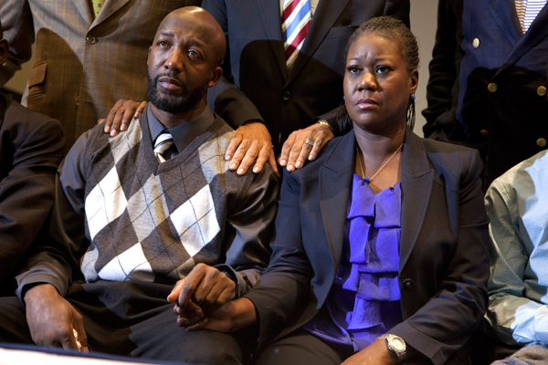 The parents of Trayvon Martin, Sybrina Fulton, right, and Tracy Martin hold hands as they watch a news conference announcing charges against George Zimmerman. (AP/Evan Vucci)