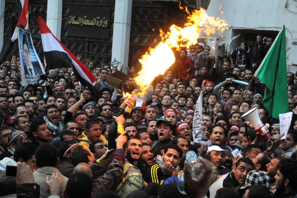 Egyptian protesters, left, spray burning aerosol over Muslim Brotherhood guards outside the Egyptian parliament. (AP)