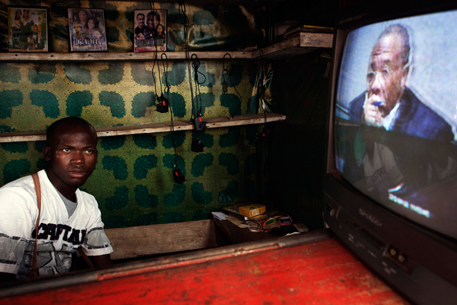 A Freetown street vendor watches a live broadcast of the  Taylor verdict being delivered. (Reuters/Finbarr O'Reilly)