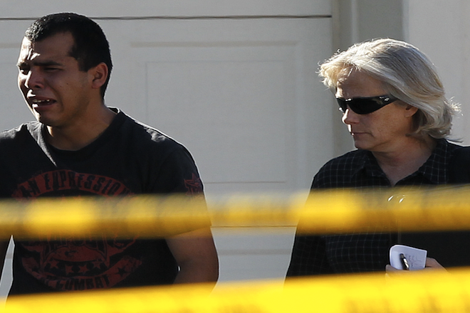 A police officer walks with a man who said he had a child inside of the home where five people were shot Wednesday, May 2, 2012 in Gilbert, Ariz. (AP Photo/Matt York)