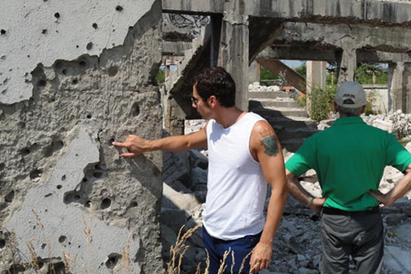 A photo of the author examining bullet holes near the cemetery where his family is buried in Bosnia. (Eldin Trebincevic)