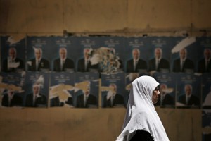 An Egyptian woman walks past defaced posters of Egyptian presidential candidate Ahmed Shafiq in Cairo, Egypt, Wednesday, May 16, 2012. (AP Photo/Manu Brabo)