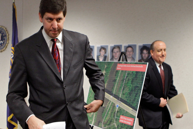 U.S. Attorney Steven Dettelbach, left, and FBI special agent in charge Stephen Anthony walk past a map showing the location of a bridge on Ohio Rt. 82. Five men, pictured on the wall behind the map, have been arrested for conspiring to blow up the bridge. (AP/Mark Duncan)