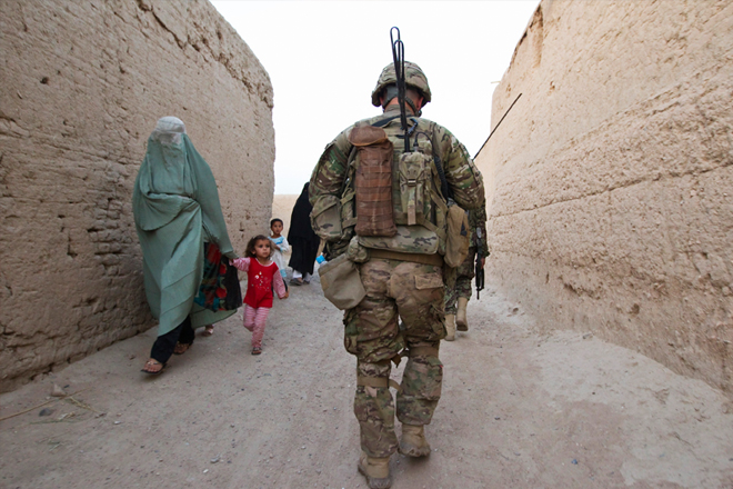 An Afghan family walks past a U.S. Army soldier in the town of Senjaray. (AP/Shamil Zhumatov)