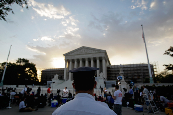 An officer stands outside the Supreme Court as media and the public gather on Thursday. (AP/David Goldman)