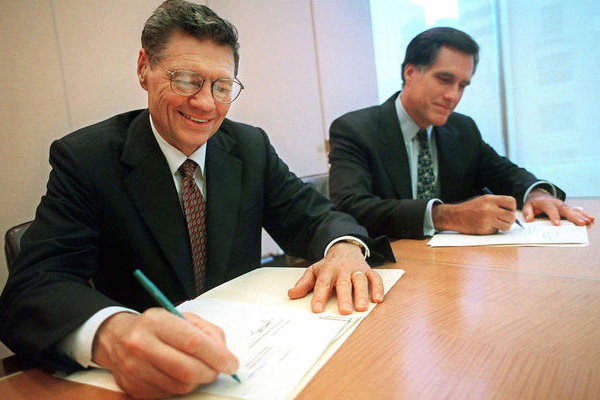 In this Sept. 25, 1998, file photo, Thomas S. Monaghan, founder and chairman of Domino's Pizza, Inc., left, and Mitt Romney sign an agreement. (AP/Scott Gries)