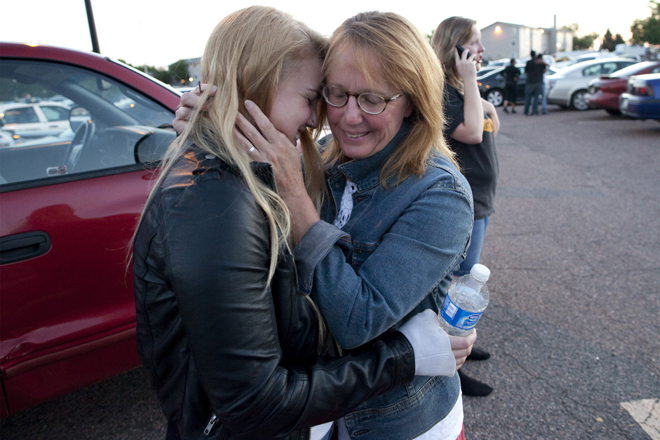 Emma Goos, 19, hugs her mother, Judy Goos, outside Gateway High School where witnesses were brought for questioning Friday, July 20, 2012, in Aurora, Colo. Emma was in the third row of the theater of the new Batman movie when the shooter entered. She helped apply pressure to a man's head who was injured. (AP Photo/Barry Gutierrez) (AP/Barry Gutierrez)