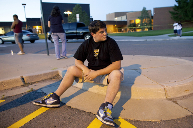 Eyewitness Chandler Brannon, 25, sits outside Gateway High School where witnesses were brought for questioning after a shooting at a movie theater showing the Batman movie "The Dark Knight Rises," Friday, July 20, 2012 in Aurora.  A gunman wearing a gas mask set off an unknown gas and fired into the crowded movie theater killing 12 people and injuring at least 50 others, authorities said. (AP Photo/Barry Gutierrez) (AP/Barry Gutierrez)