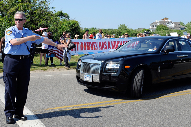 A Southampton police officer directs a Rolls Royce around protestors outside the estate of David Koch before a fundraiser for Mitt Romney on Sunday. (AP/Kathy Kmonicek)