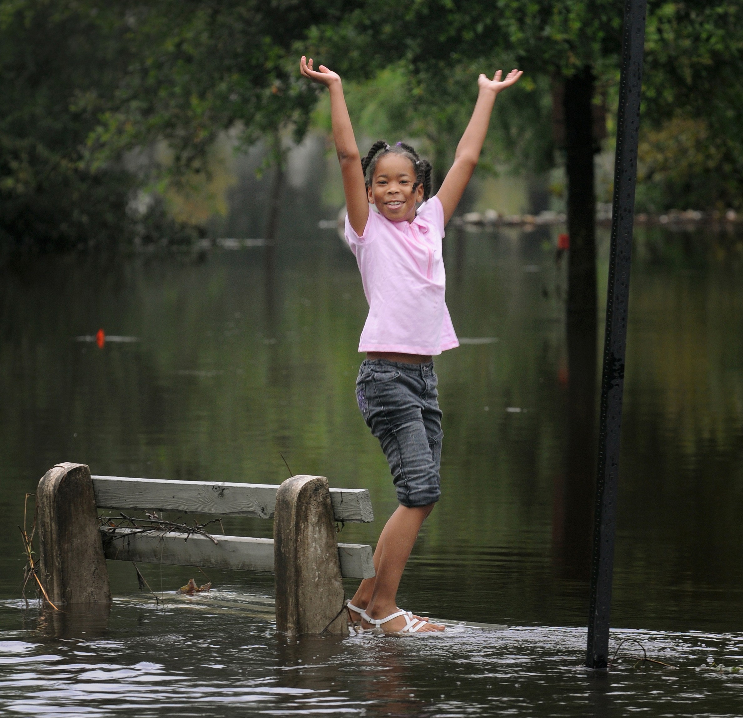 Journey Wooten, 8, stands on the base of a bench that is submerged in Jacksonville, Fla.  (AP/The Florida Times-Union, Kelly Jordan)