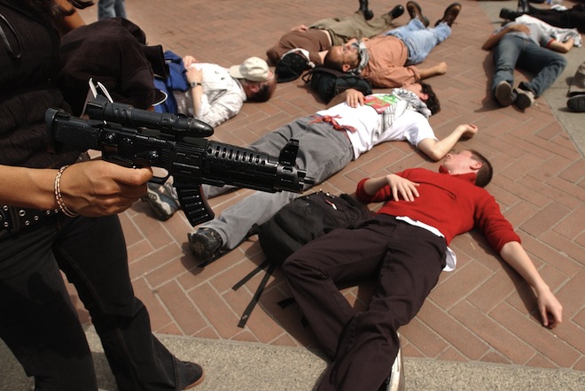 A protester holding a plastic gun stands over other demonstators with the group "Students for Justice in Palestine," during a mock "die-in"  at the steps of Sproul Plaza, Wednesday, April 9, 2003, on the University of California at Berkeley campus in Berkeley, Calif. (AP Photo/Ben Margot)