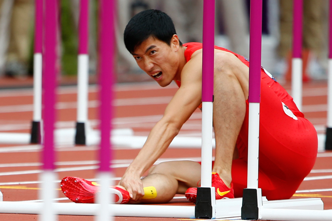 Liu Xiang holds his leg after suffering an injury at the 2012 Olympic Games on Monday. (Reuters/Kai Pfaffenbach)