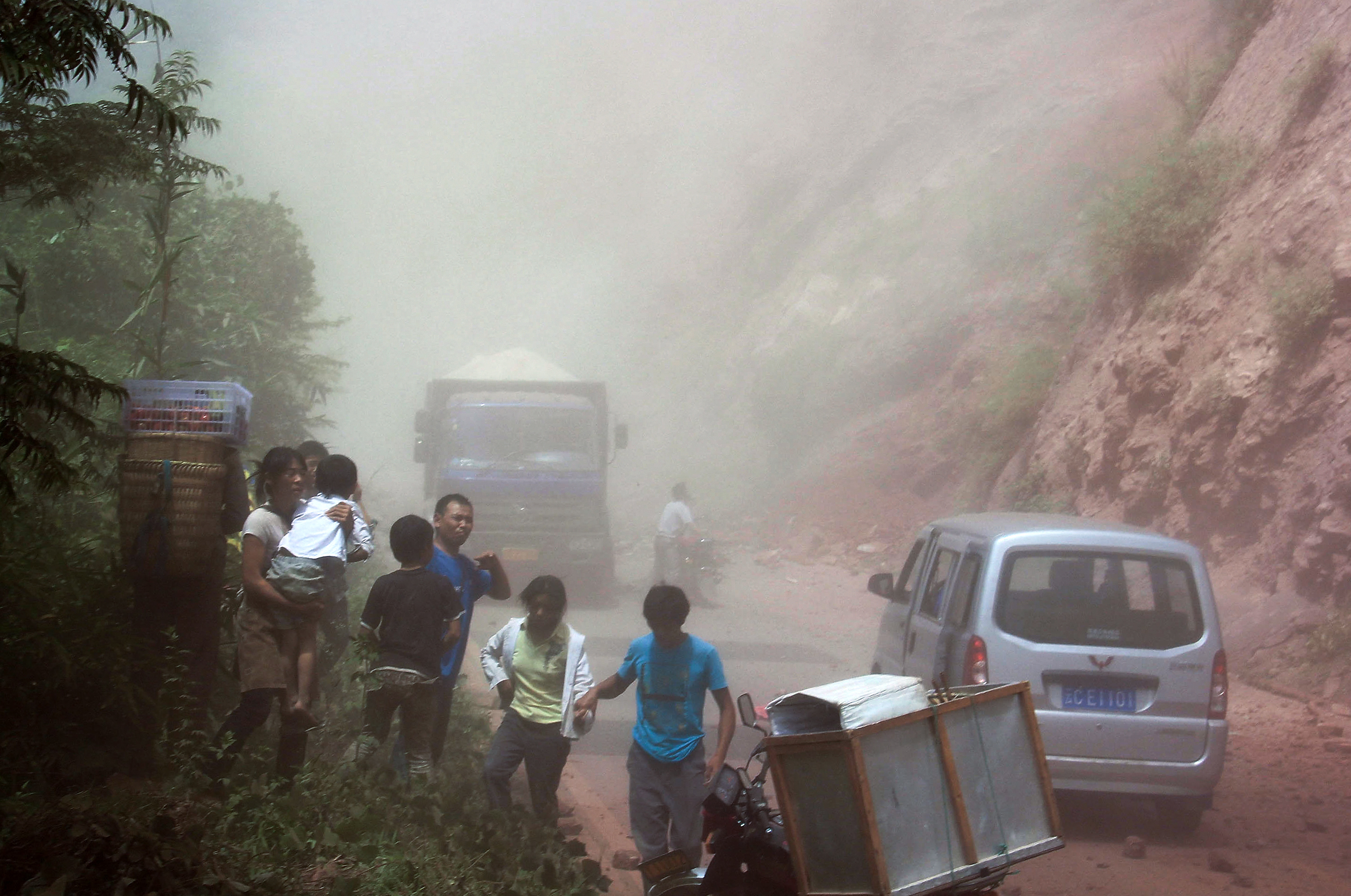 People run as rocks fall near their vehicles after the area was hit by an earthquake in Zhaotong town, Yiliang County, southwest China's Yunnan Province, Friday, Sept. 7, 2012. (AP Photo) CHINA OUT