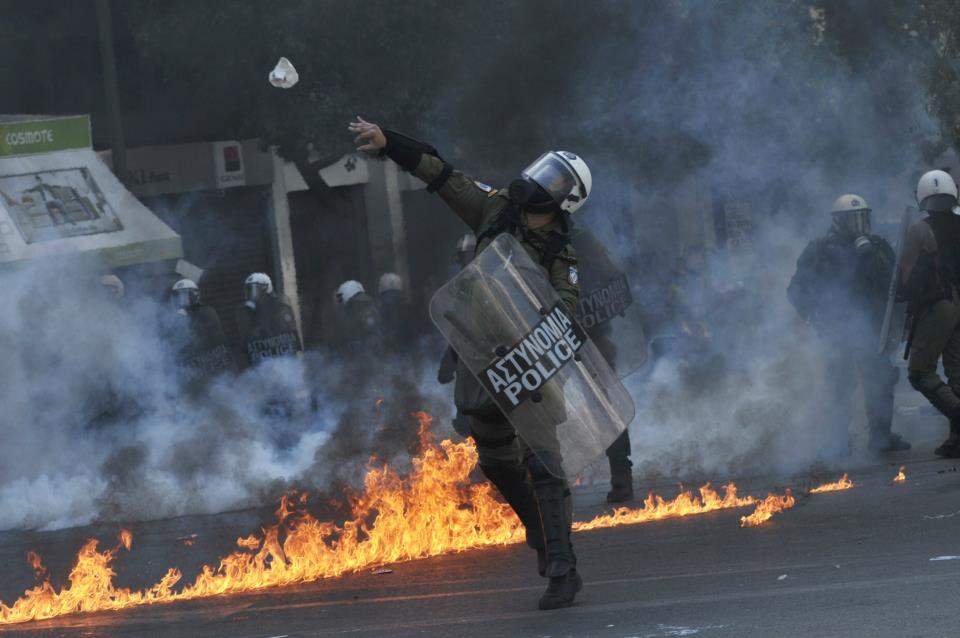 Riot cop throws stone at protesters (Twitter user Helena Kasp)