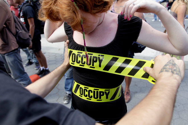 "Occupy" security-style tape is stuck to Laura Nagy during an Occupy Wall Street anniversary concert in Foley Square in New York on Sunday, Sept. 16, 2012. The Occupy Wall Street movement will mark its first anniversary on Monday. (AP/Seth Wenig)