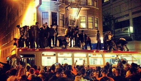 Revelers stand atop a San Francisco bus (Twitter)
