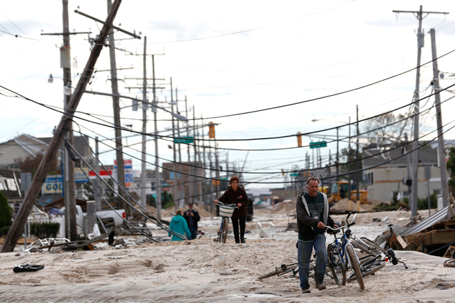 People walk through sand that washed up from the beach and onto Route 35 during superstorm Sandy, Wednesday, Oct. 31, 2012, in Lavallette, N.J. (AP/Julio Cortez)