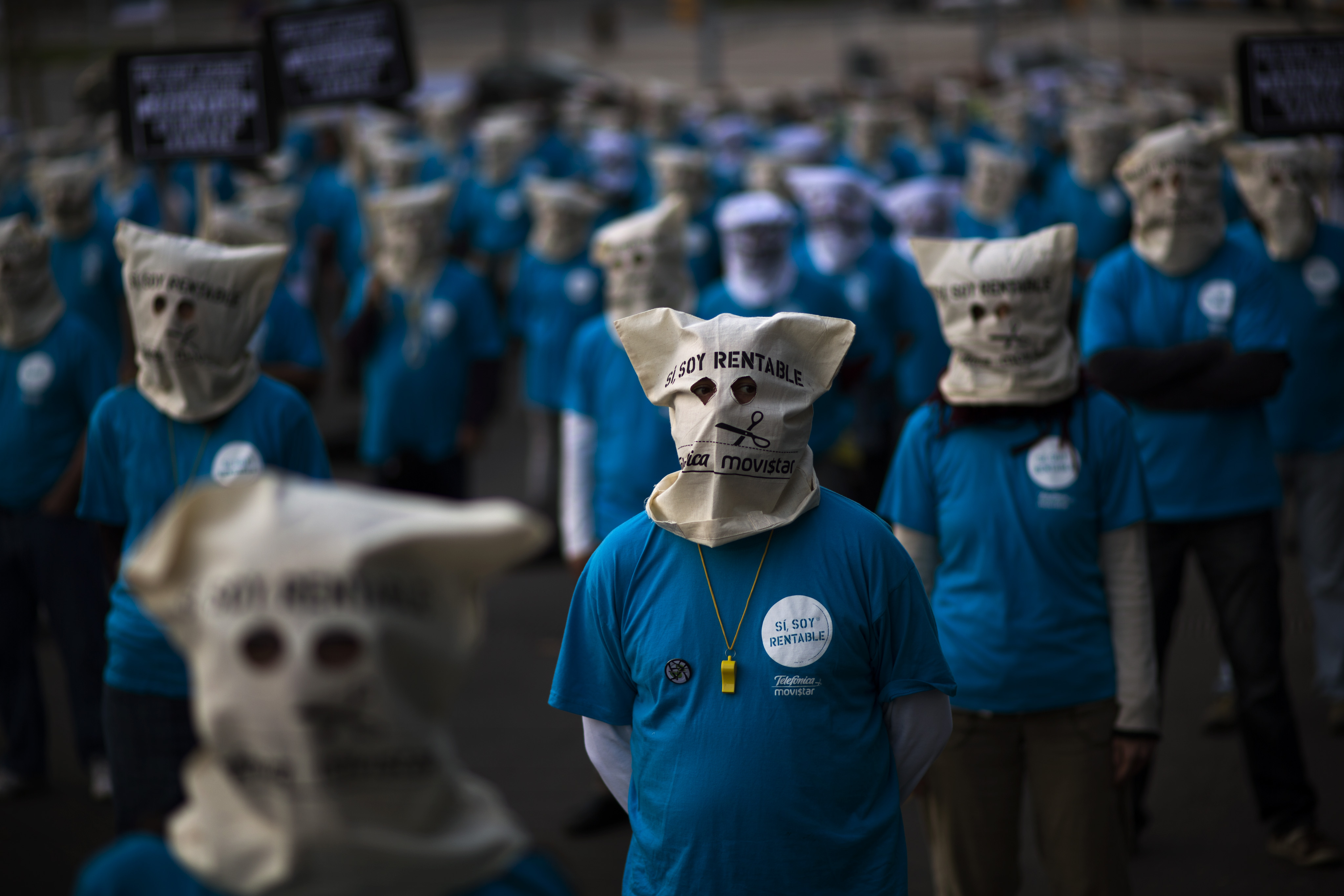 Masked demonstrators, employees from the Telefonica phone company, protest on a street near a building where executives from the same company are participating in a business meeting in Barcelona, Spain (AP/Emilio Morenatti)