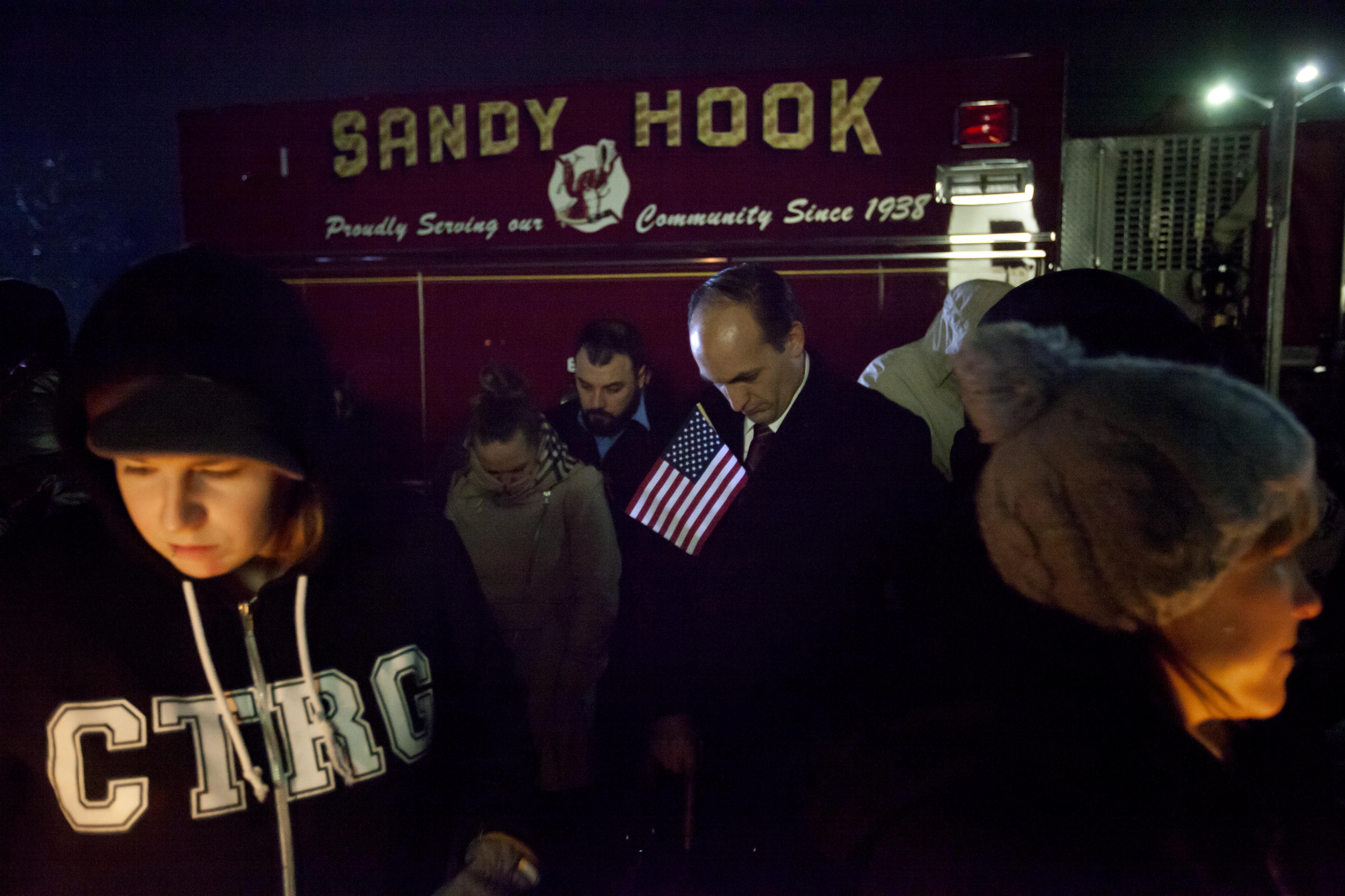 Mourners listen to a memorial service over a loudspeaker outside Newtown High School for the victims of the Sandy Hook Elementary School shooting. (AP/David Goldman)