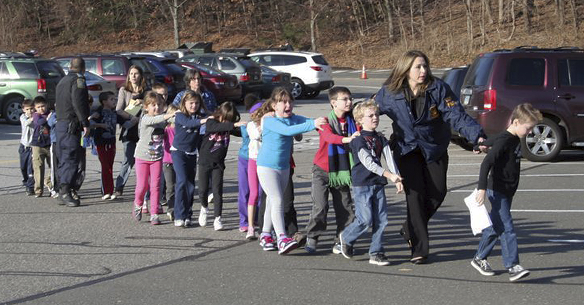 In this photo provided by the Newtown Bee, Connecticut State Police lead children from the Sandy Hook Elementary School in Newtown, Conn. (Associated Press)