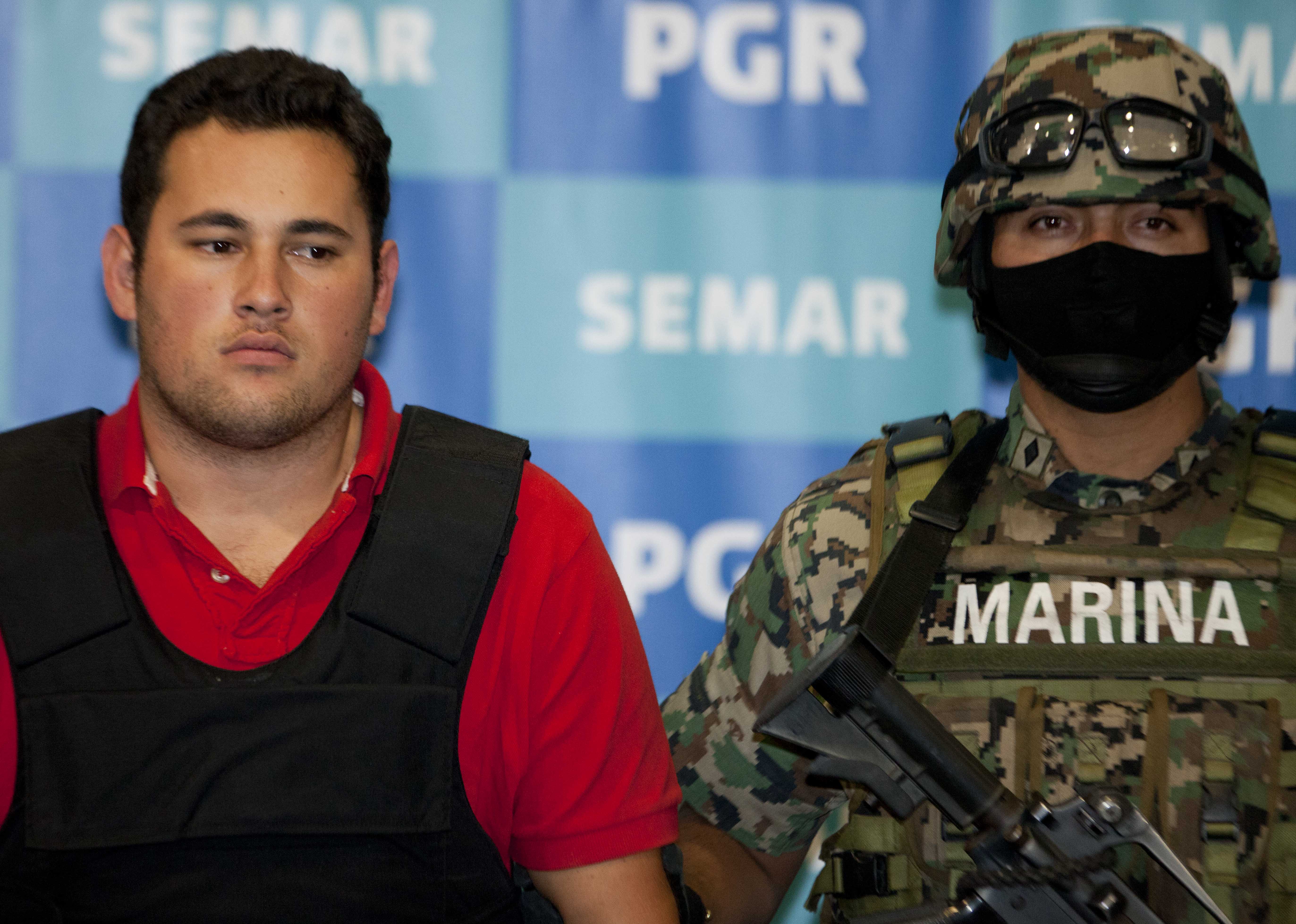 A Mexican marine escorts Jesus Alfredo Guzman Salazar, left, during his presentation to the media in Mexico City. (AP/Eduardo Verdugo)