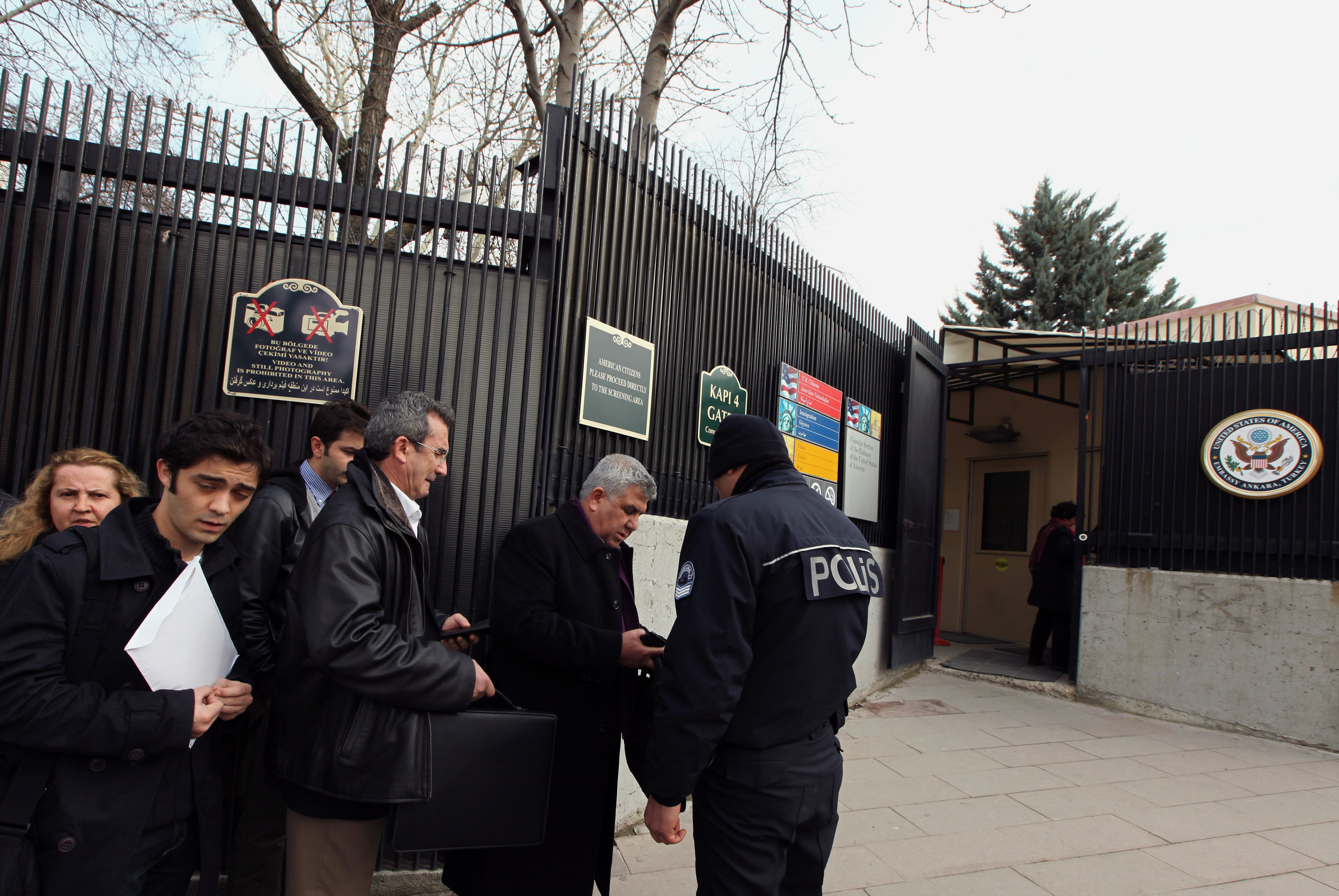 A Turkish police officer stands in front of people waiting for visas near the side entrance of the U. S. embassy. (AP/Burhan Ozbilici)