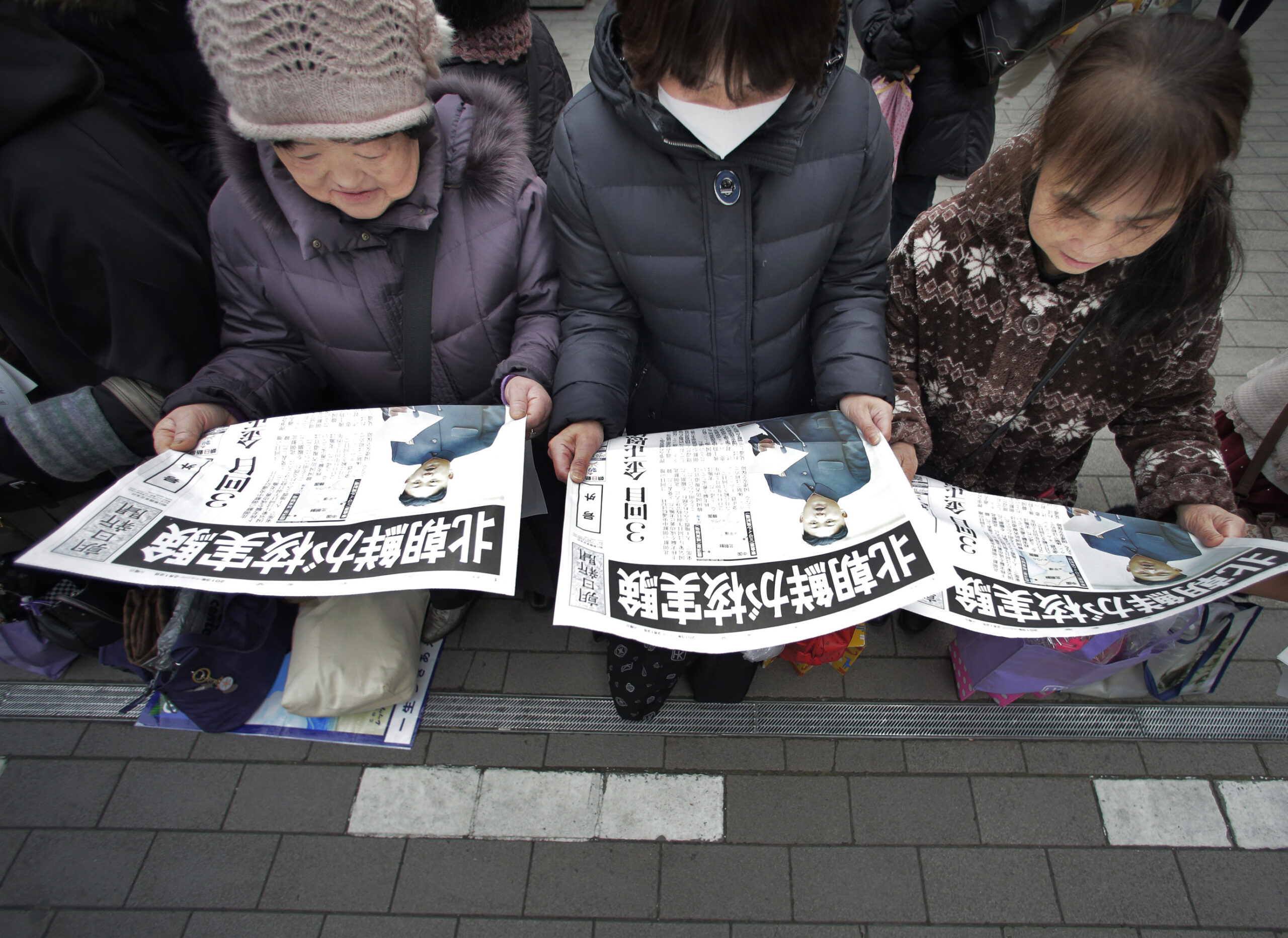 Passers-by read a delivered extra edition of a Japanese newspaper reporting North Korea's nuclear test, in Tokyo Tuesday, Feb. 12, 2013. (AP/Itsuo Inouye)