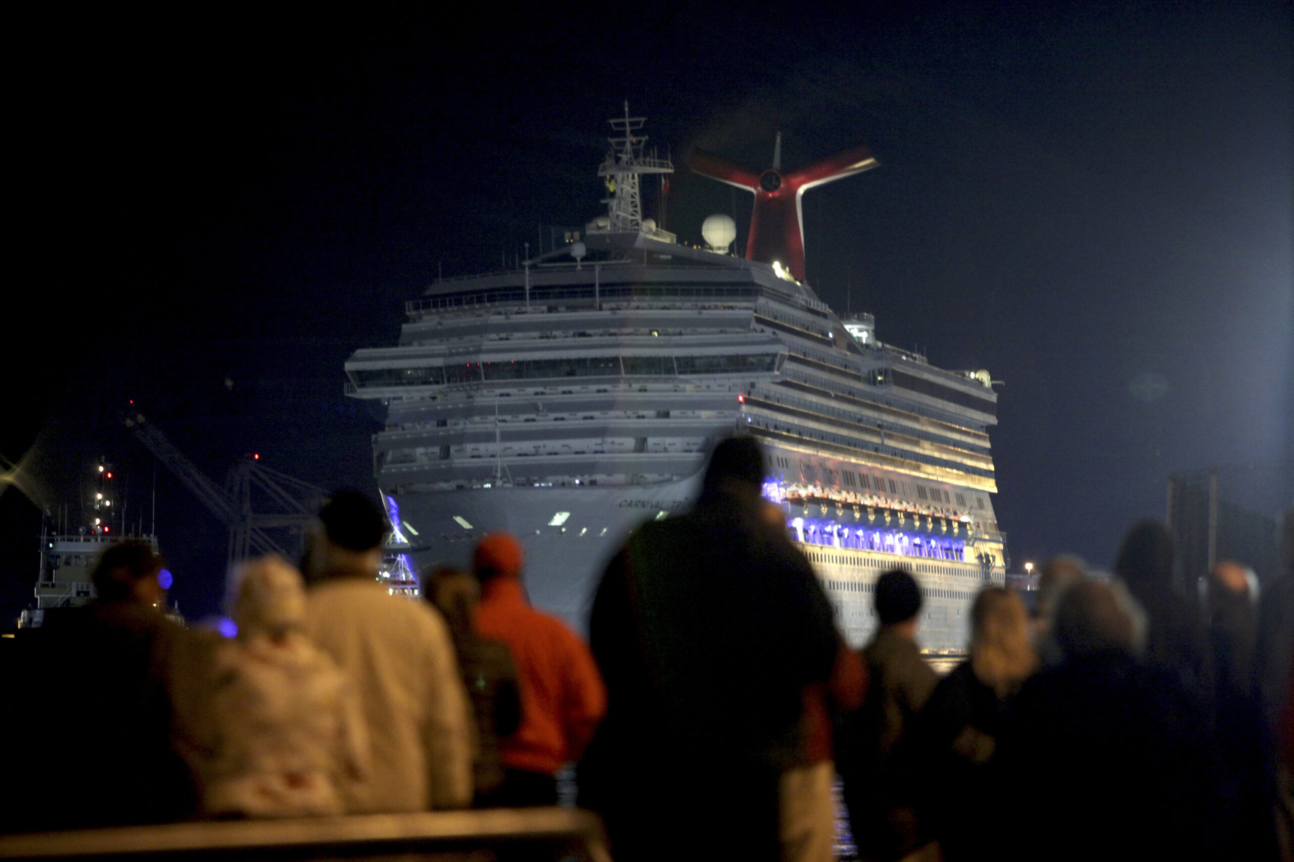 The Carnival Triumph cruise ship is towed toward the dock as spectators watch at the port of Mobile, Ala. (Reuters)