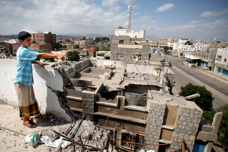 A boy gestures to damage on a house caused by an air strike last year that was targeting al Qaeda-linked militants, in the southern Yemeni town of Jaar February 1, 2013. (Reuters/Khaled Abdullah Ali Al Mahdi)