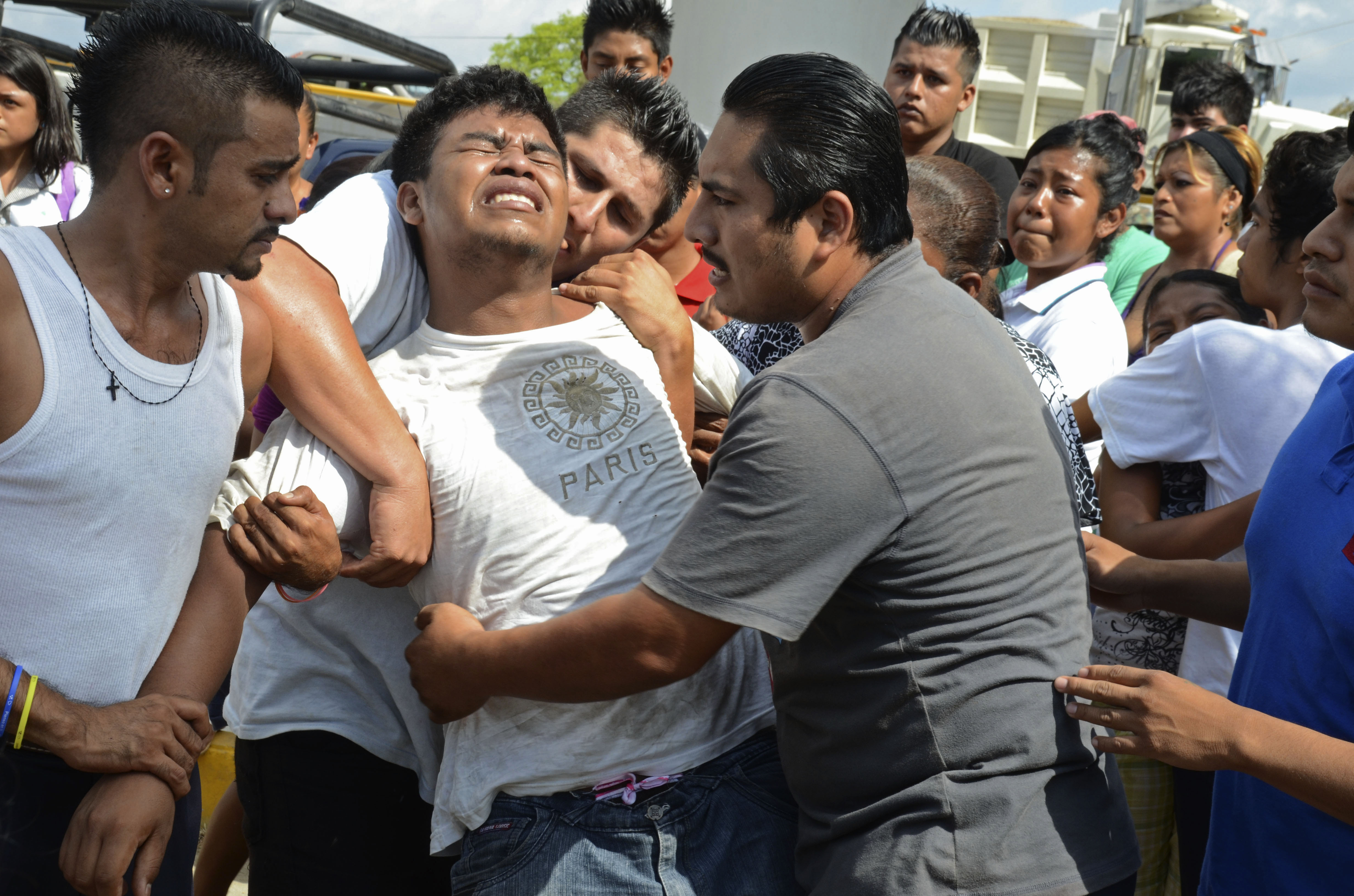 A distraught relative is held back after three men on a public bus were killed by unknown gunmen in the Pacific resort city of Acapulco, Mexico, Monday March 1, 2013. (AP/Bernandino Hernandez)