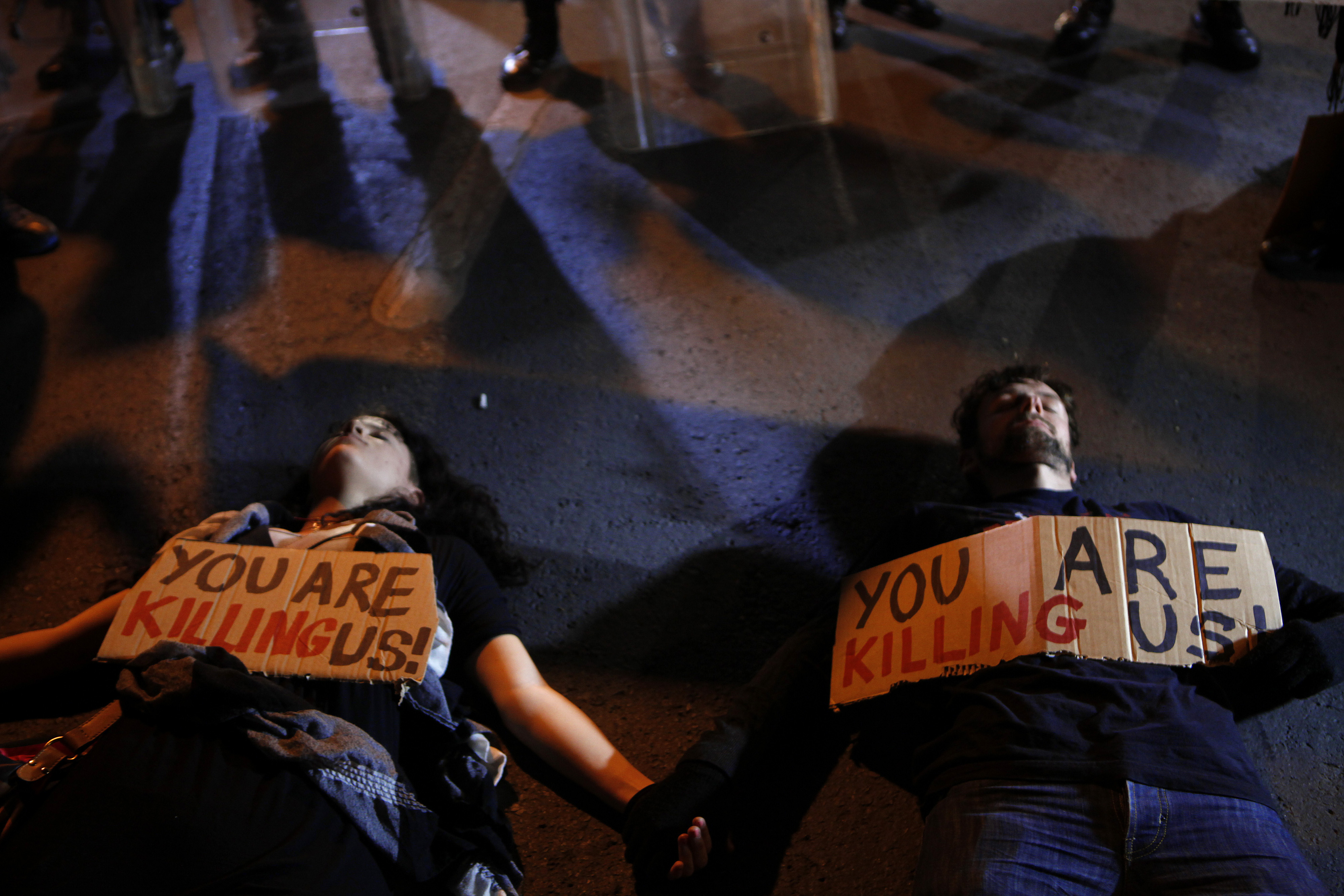 Protesters line on the ground in front of riot police in Nicosia, Cyprus. (AP/Petros Karadjias)