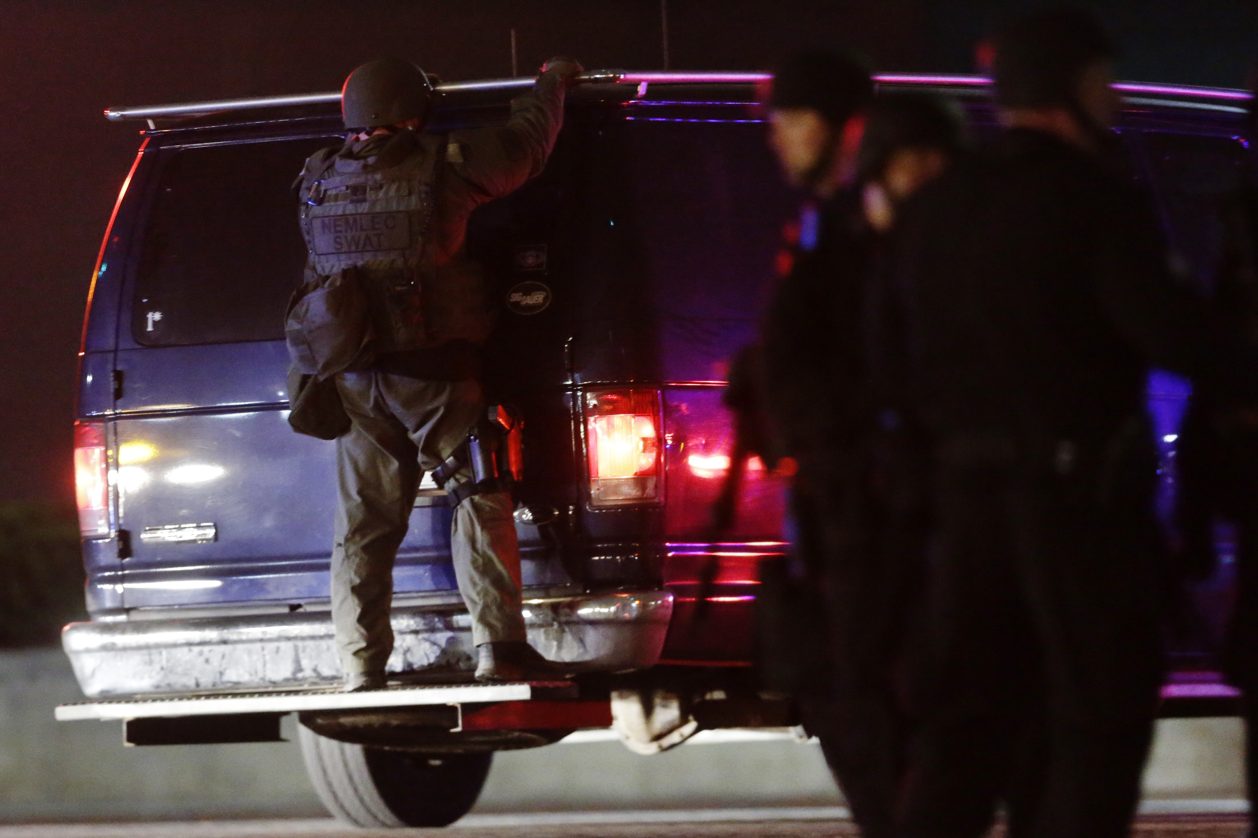 A police officers rides on the back of a van at a staging area as a manhunt is conducted for a suspect Friday, April 19, 2013, in Watertown, Mass. (AP/Matt Rourke)