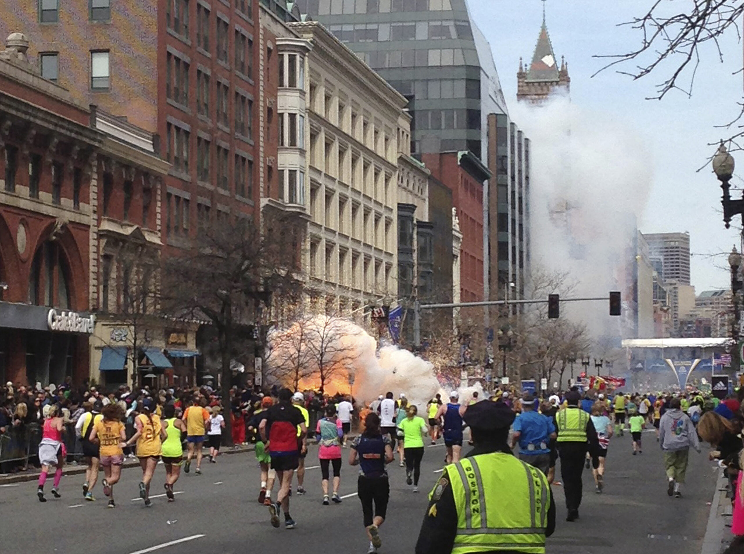 Runners continue to run towards the finish line of the Boston Marathon as an explosion erupts near the finish line. (Reuters/Dan Lampariello)