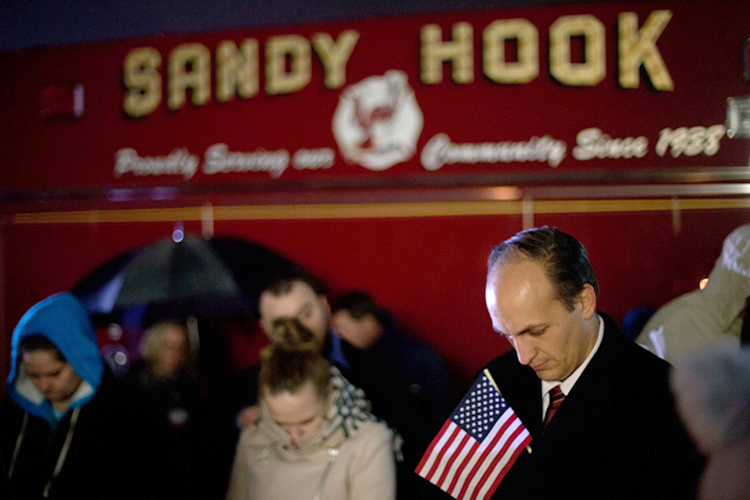 Mourners listen to a memorial service over a loudspeaker outside Newtown High School for the victims of the Sandy Hook Elementary School shooting, Sunday, Dec. 16, 2012, in Newtown, Conn. (AP/David Goldman)