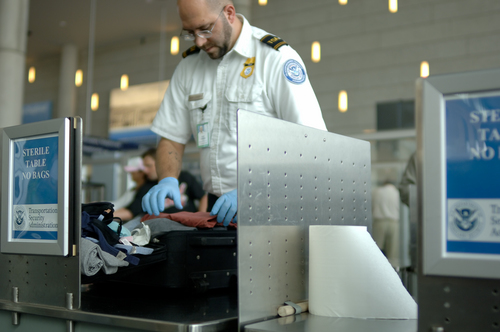 A TSA agent searches luggage at an airport (Carolina K. Smith)