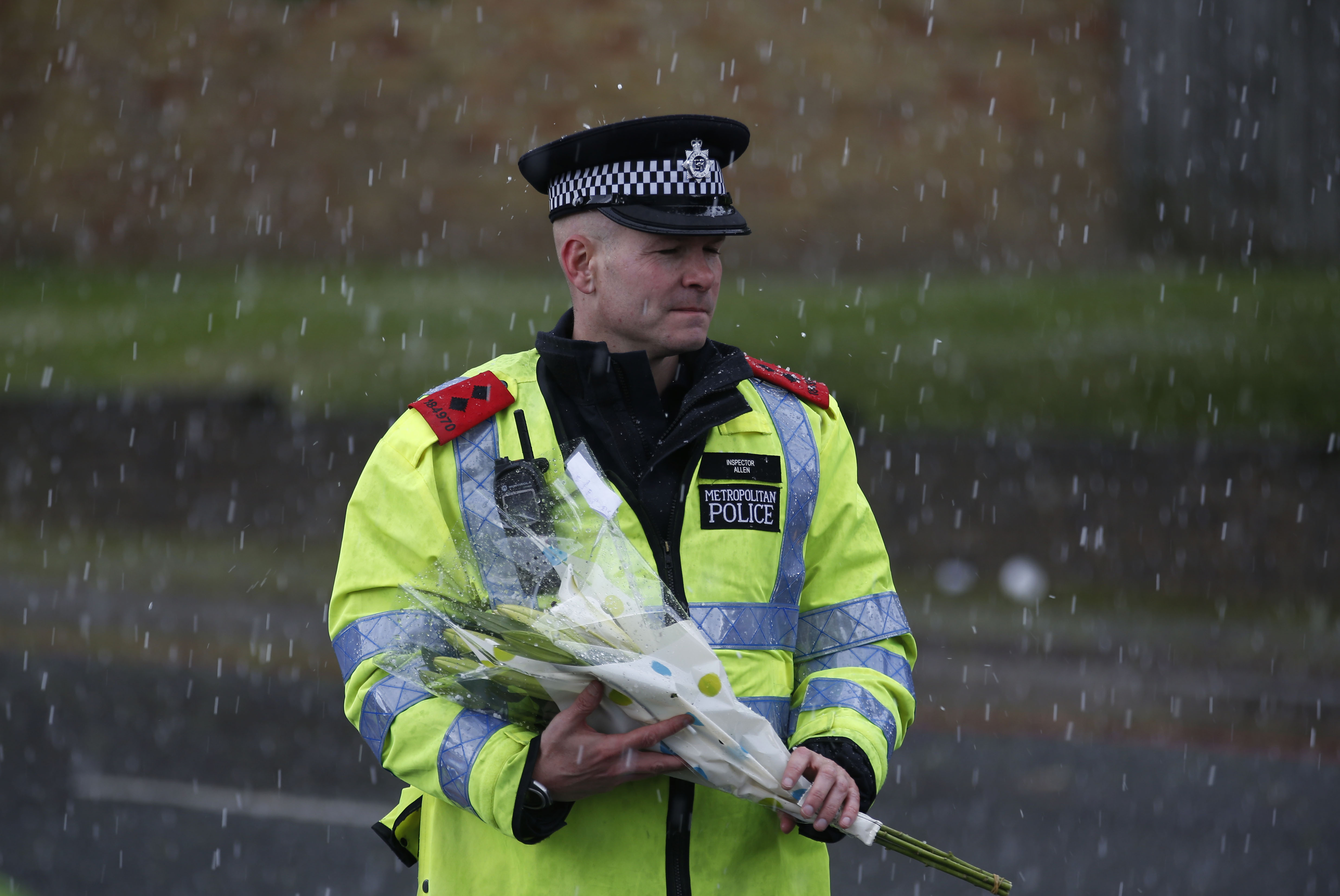 A police officer holds a floral tribute handed to him by a member of the public to be placed at the scene of a terror attack in Woolwich, southeast London, Thursday, May 23, 2013. (AP/Sang Tan)