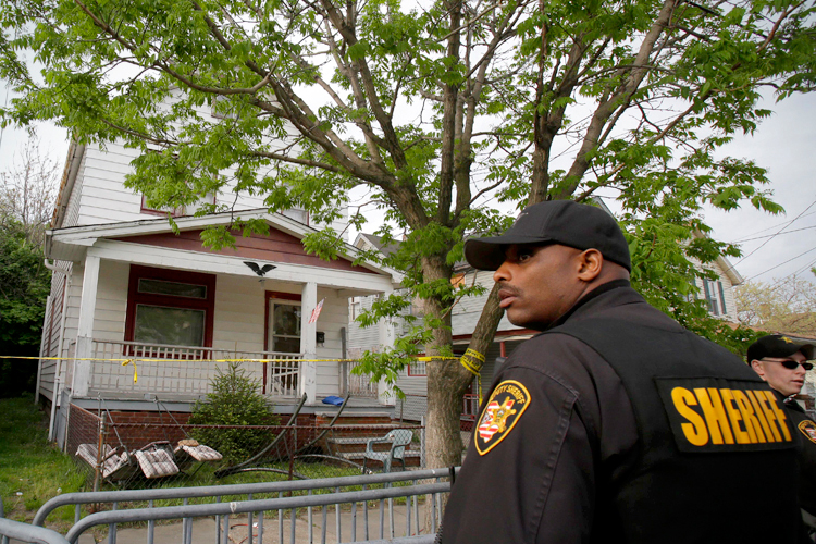 A sheriff deputy stands outside the Cleveland house where Amanda Berry, Gina DeJesus and Michelle Knight were allegedly held captive for almost a decade. (AP/Tony Dejak)