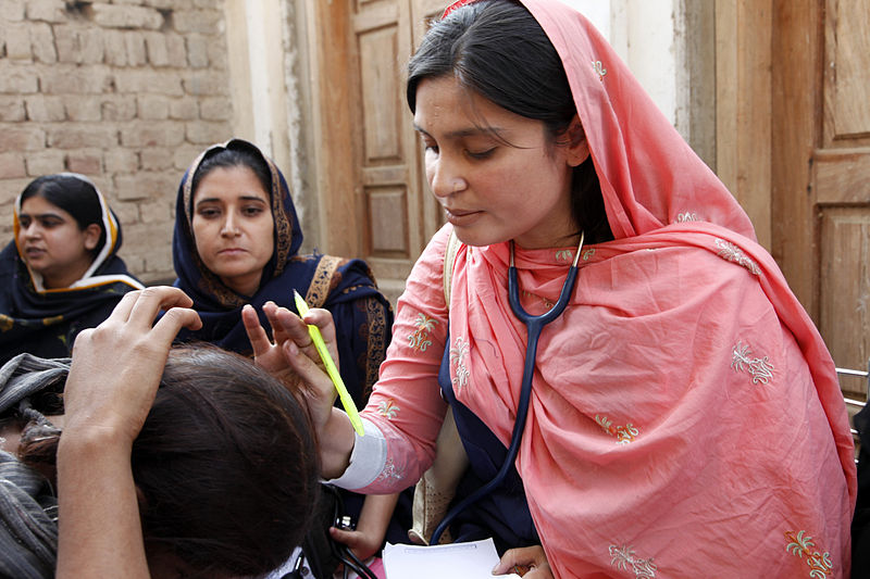 A female doctor with the International Medical Corps examines a woman patient at a mobile health clinic in Pakistan (Wikimedia Commons)