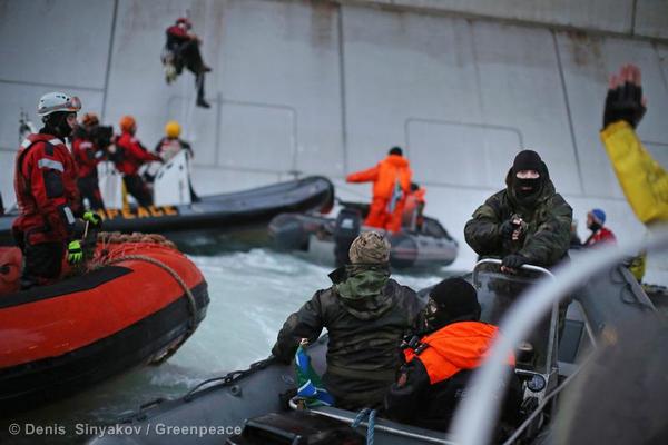 A Russian Coast guard officer is seen pointing a gun at a Greenpeace International activist as five activists attempt to climb the 'Prirazlomnaya,' an oil platform operated by Russian state-owned energy giant Gazprom platform in Russias Pechora Sea. (Denis  Sinyakov/Greenpeace)